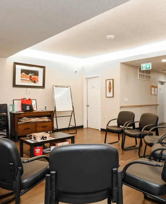 chairs placed in a circle around a central coffee table. all within the central room of the Inii Healing House (IHH)